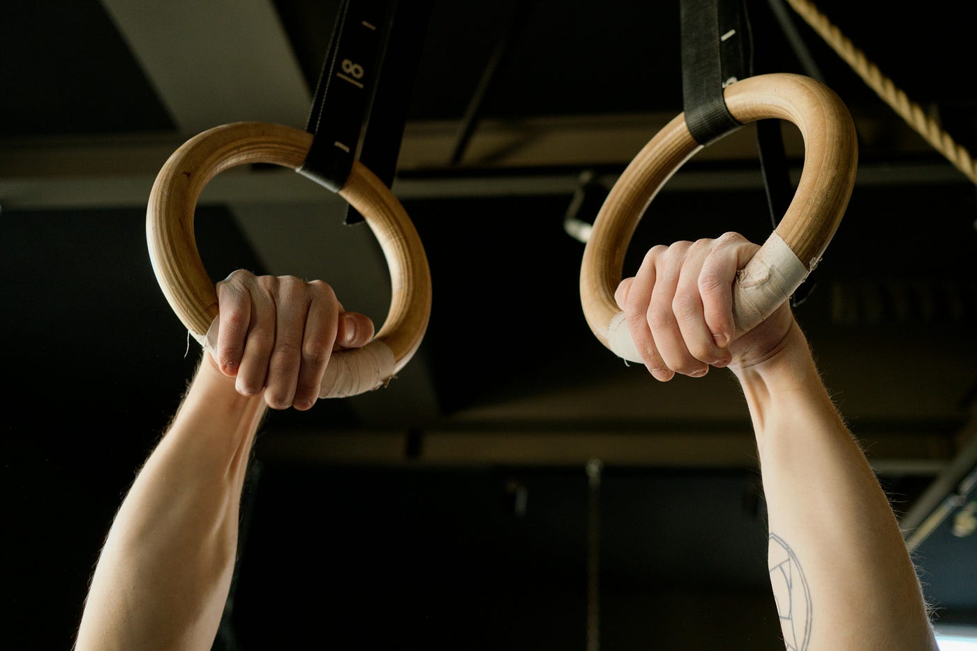Close-up of hands gripping a pair of wooden gymnastics rings
