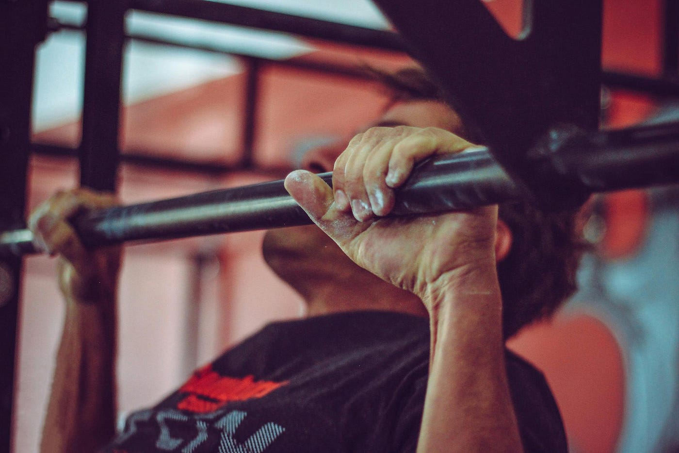 Close-up of chalked hands gripping a pull-up bar during a pull-up