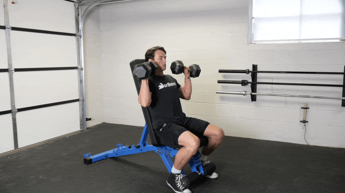 Animation of a man doing a seated dumbbell shoulder press on an upright bench, pressing the dumbbells overhead
