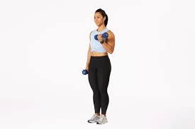 Woman doing standing dumbbell curls, one dumbbell curled to her shoulder and the other at her side